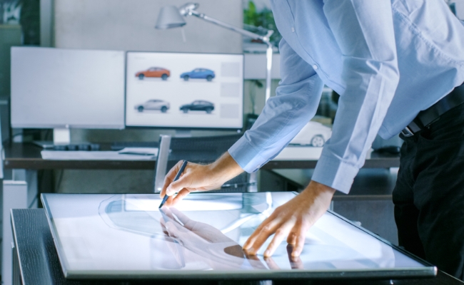 Man designing an automobile, car drawings in background
